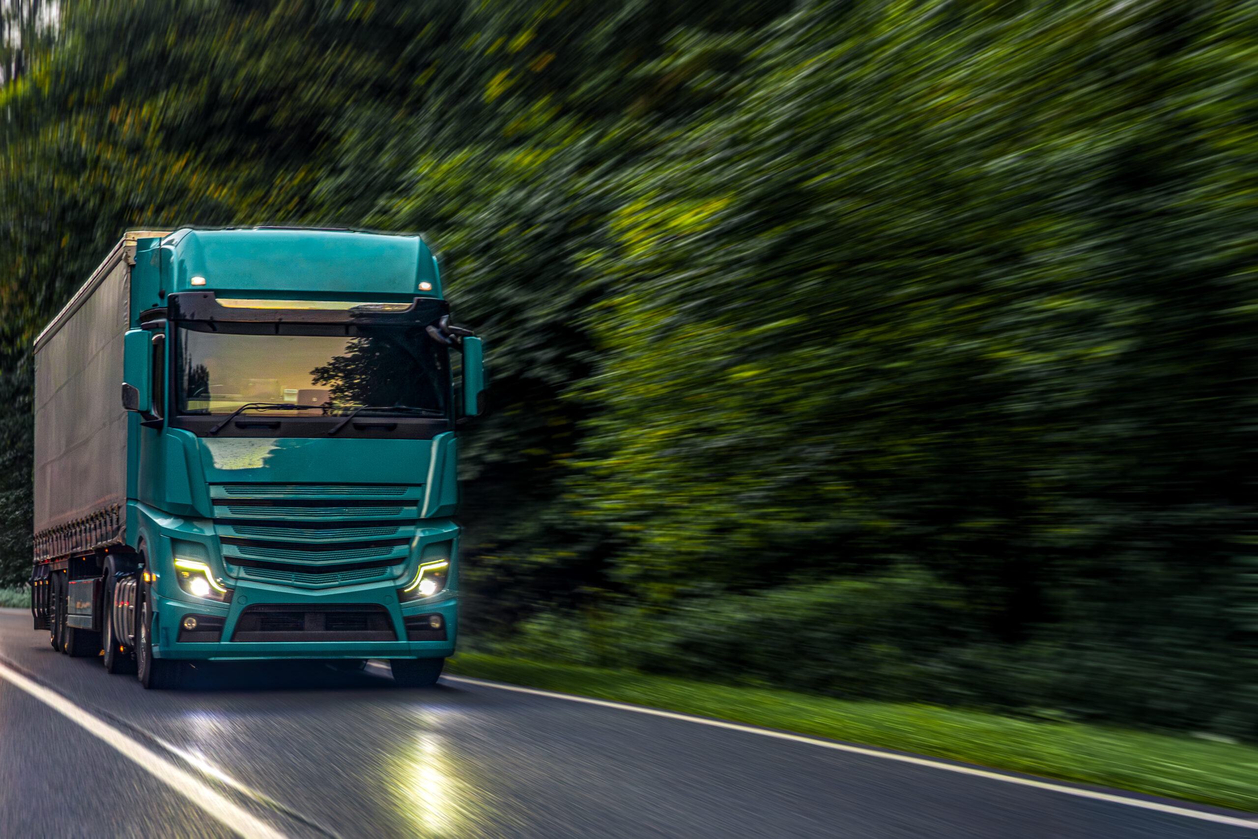 A powerful emerald green truck driving fast through a forest road, symbolizing innovation, energy, and modern logistics strength.